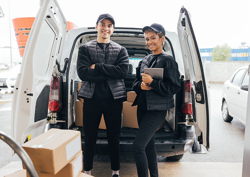 Portrait of confident delivery man and woman in uniform standing