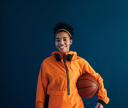 Smiling and confident professional basketball player wearing orange sportswear looking at camera