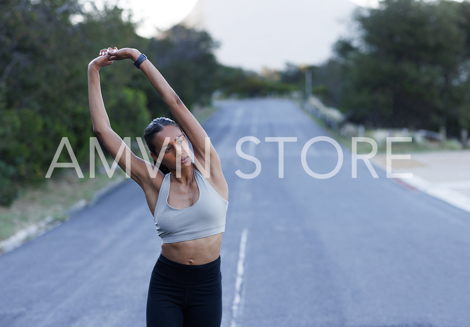 Young slim woman in fitness wear warming up hands while walking on an abandoned road