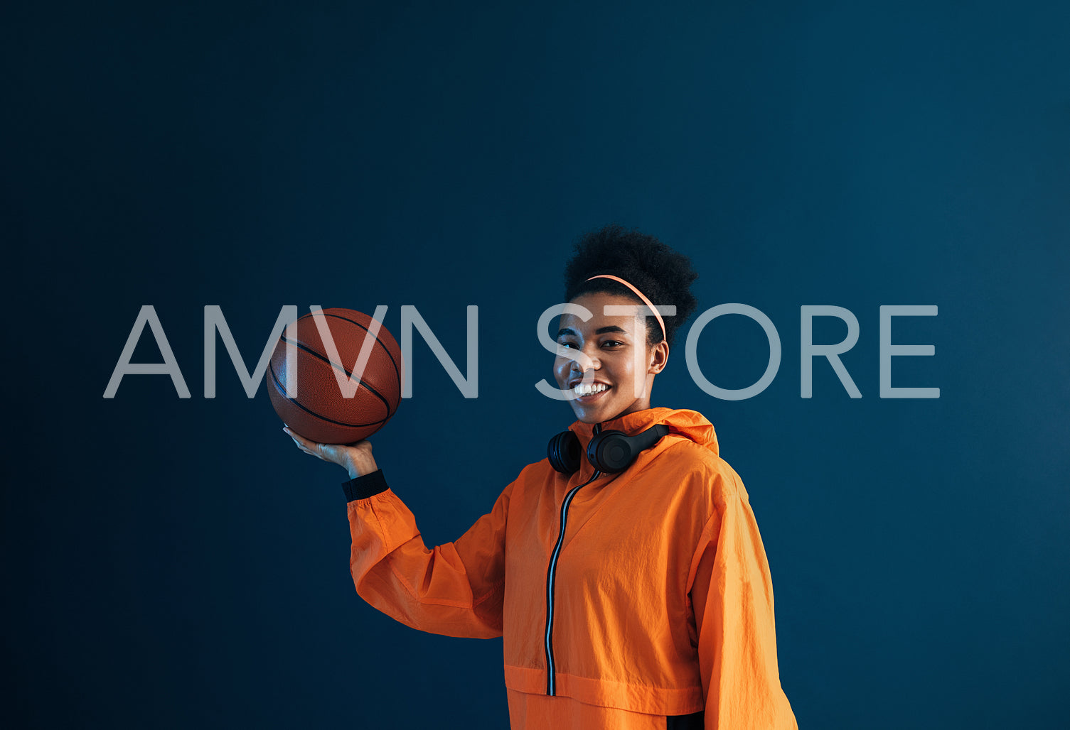 Portrait of a happy professional basketball player wearing orange fitness attire and looking at camera