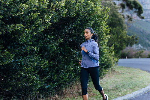 Young female running outdoors in a natural park. Slim female doing an intense run in the morning.