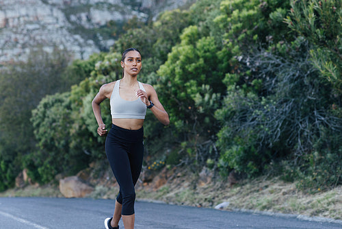 Young female runner practicing outdoors. Slim jogger in fitness wear runner on an abandoned road.