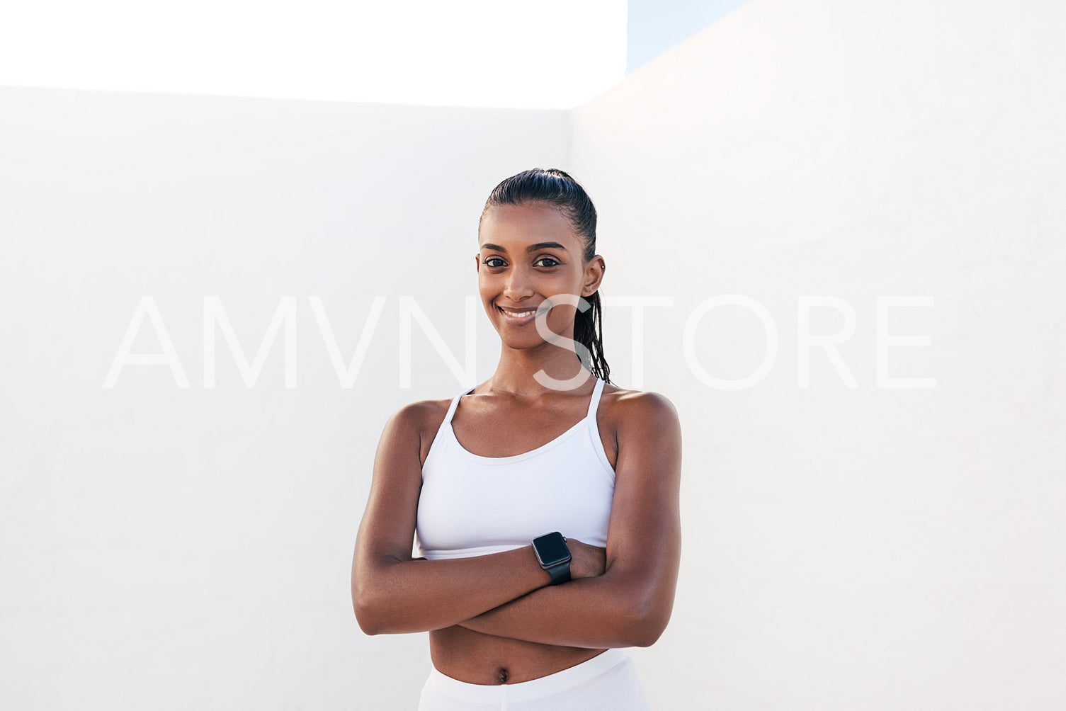 Portrait of a smiling woman in sportswear with crossed arms. Confident female athlete looking at camera outdoors.