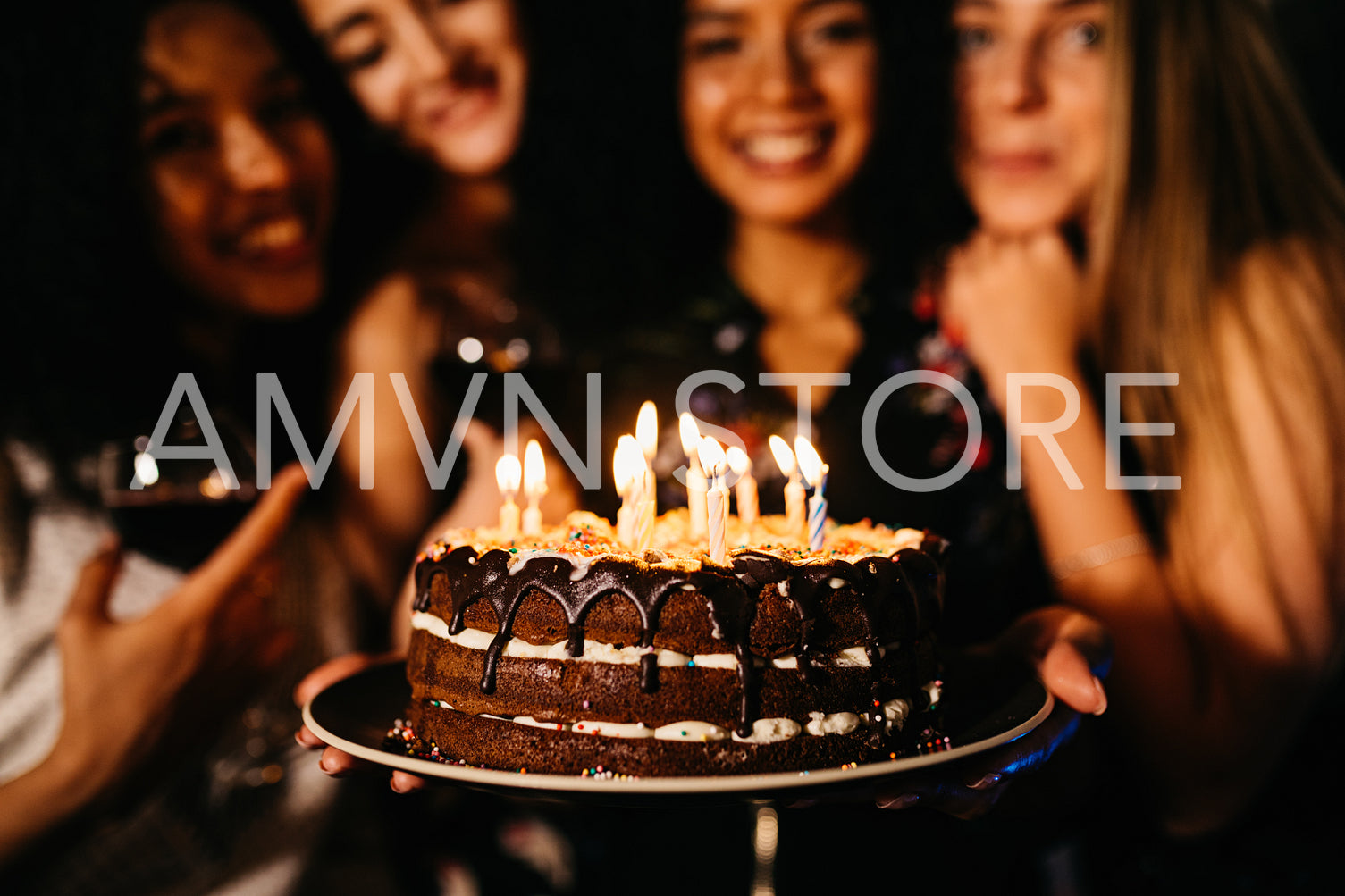 Close up shot of woman holding birthday cake standing indoors with friends