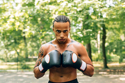 Close up portrait of a sweated kickboxer with gloves and mouth guard looking at the camera