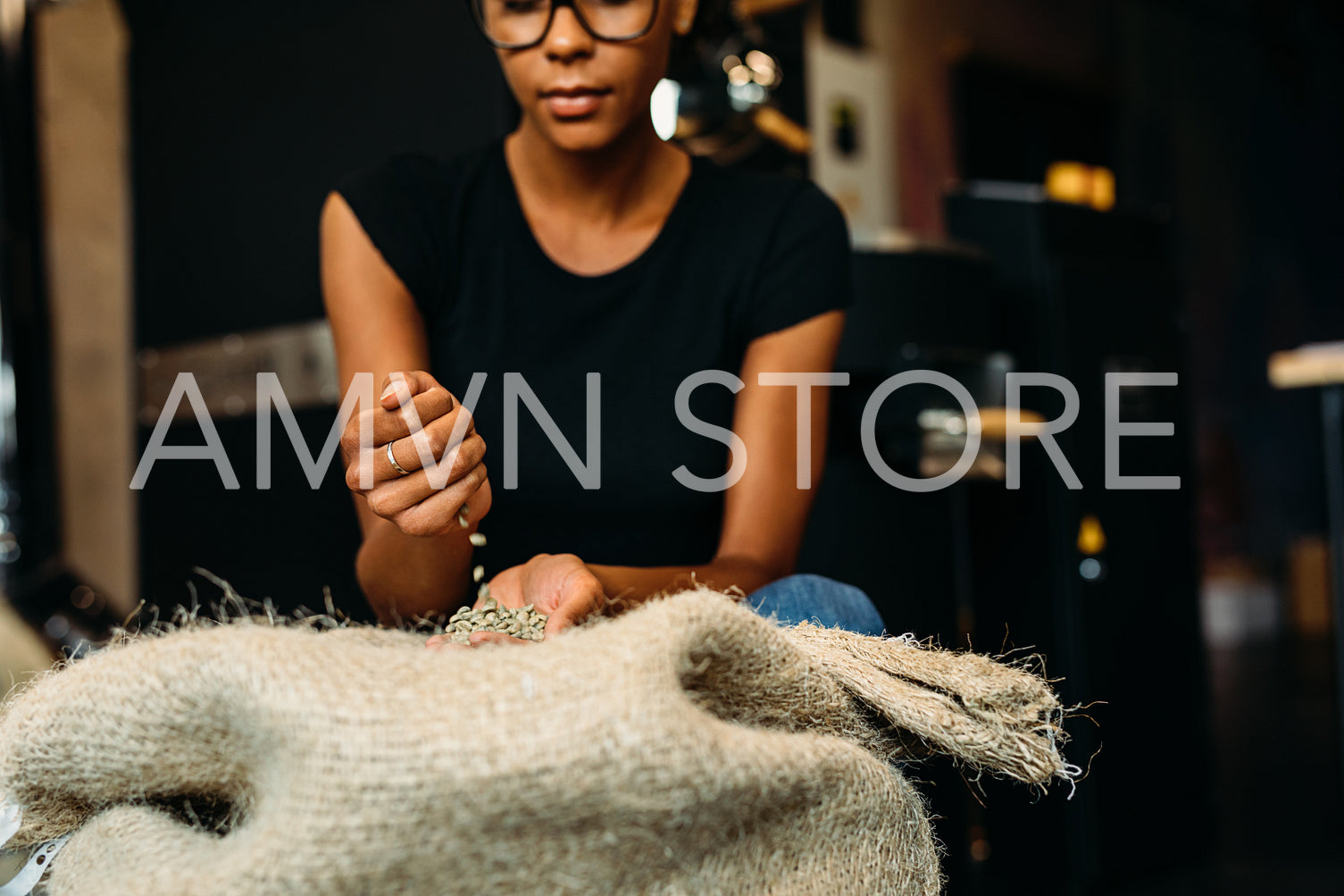 Woman inspecting fresh coffee beans in her coffee shop before roasting	