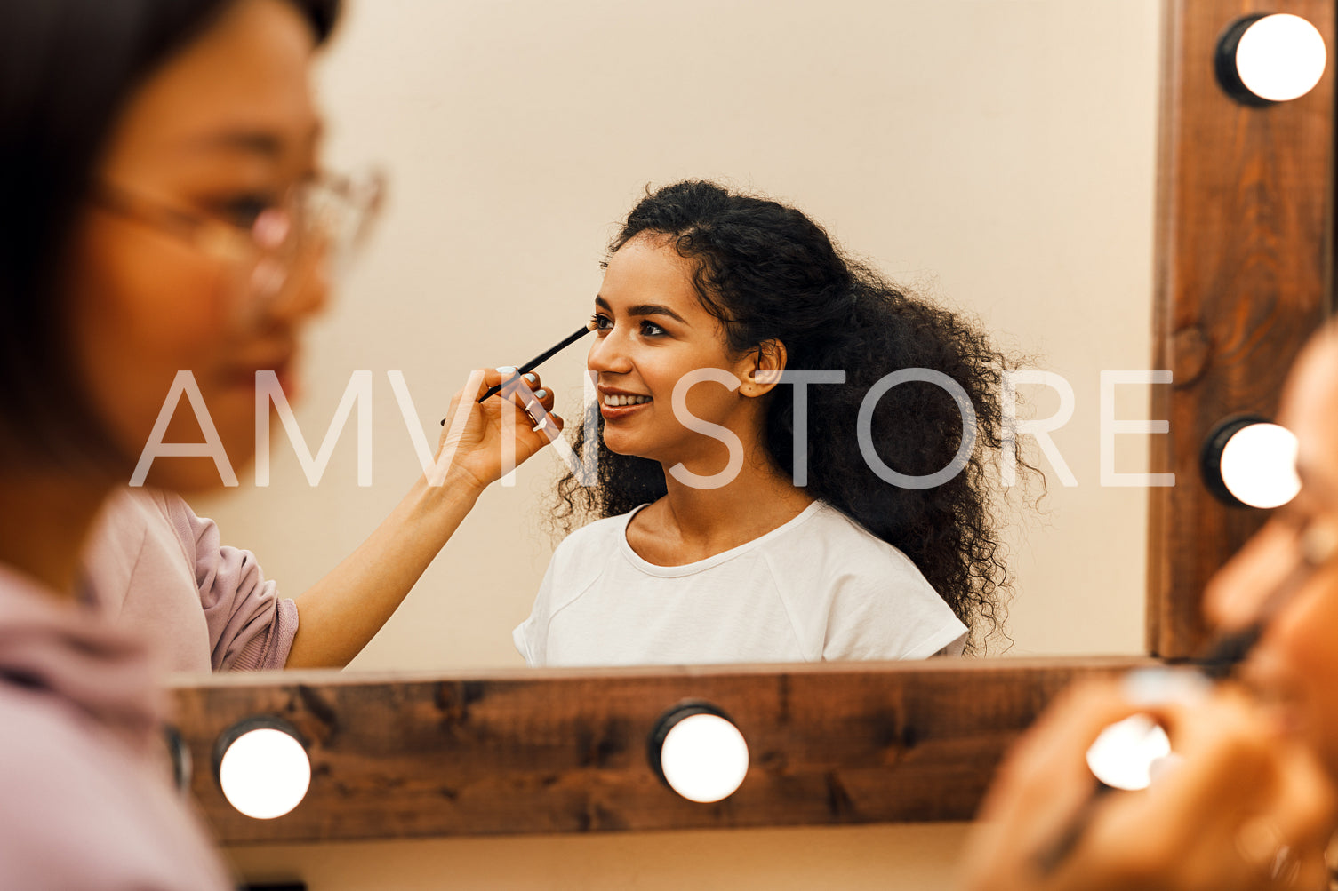 Side view of a makeup artist preparing model for a photo shoot	
