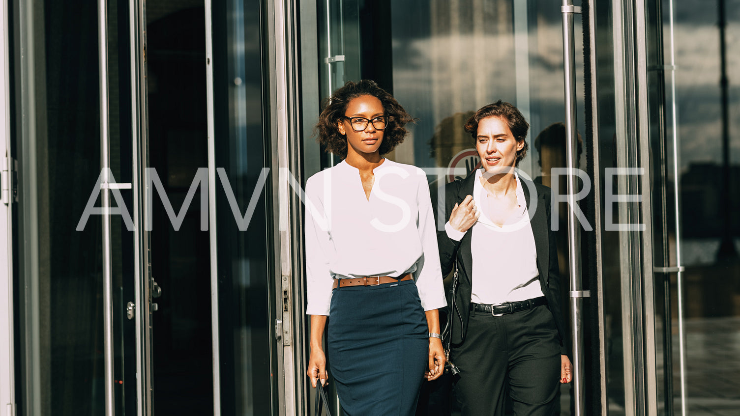 Two women out office building. Business colleagues walking together.	