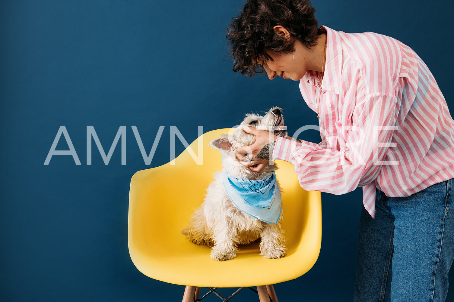 Side view of young pet owner touching her dog who is sitting on yellow chair