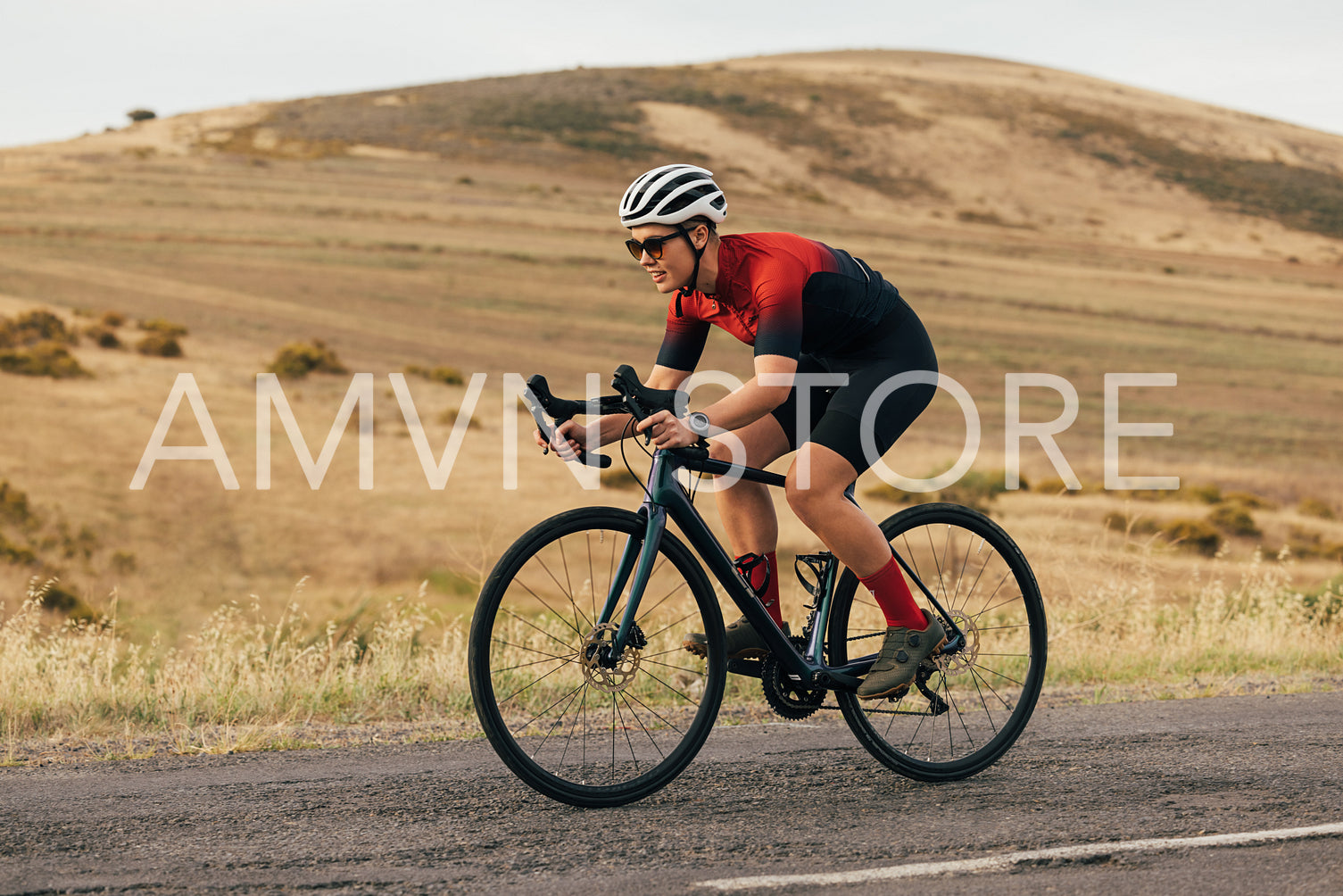 Professional woman cyclist wearing a helmet and sunglasses exercising on road bike