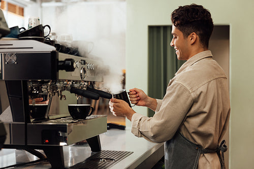 Side view of a barista using a coffee machine. Coffee shop owner preparing coffee.