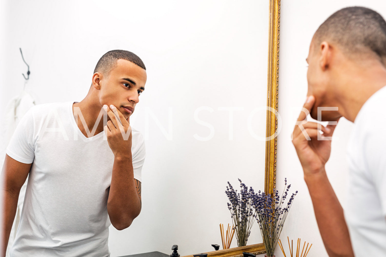 Portrait of a handsome young man examining his face in the bathroom mirror	