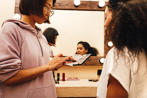 Makeup artist with her palette choosing color. Two people preparing for photo shoot.