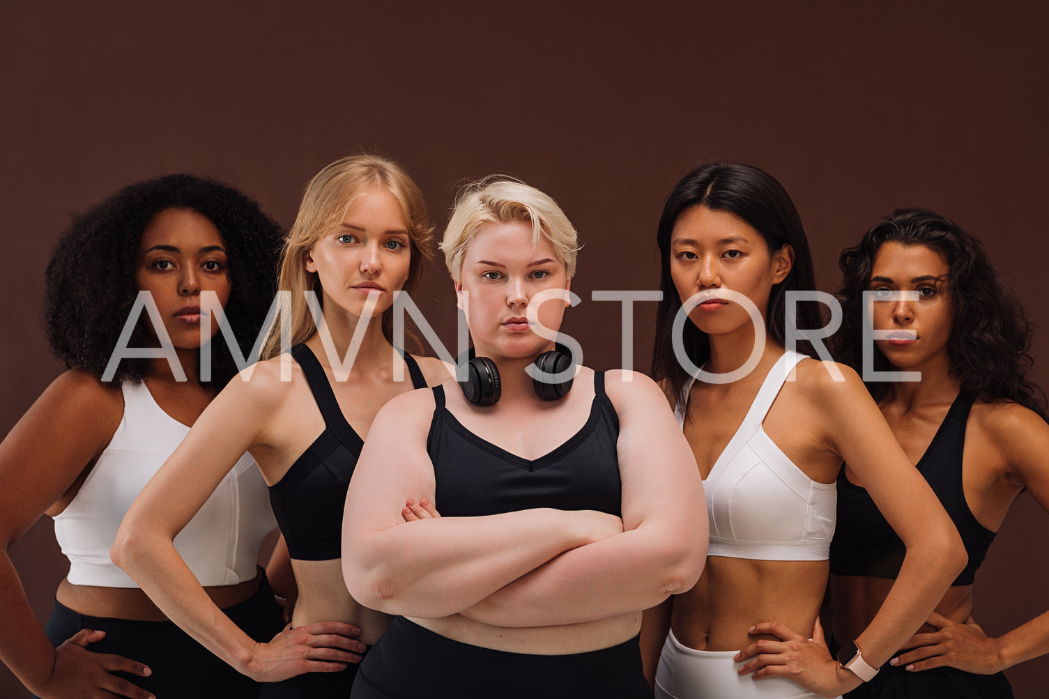 Five confident women in sportswear standing together. Females of