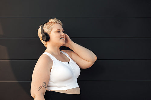 Side view of smiling woman in fitness clothes listening to music