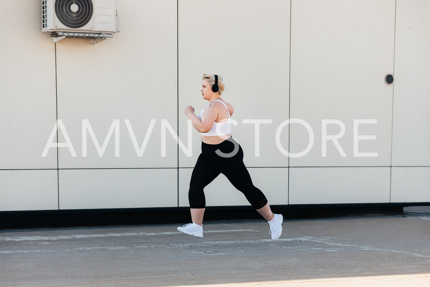 Side view of a woman with plus size body running at wall outdoors	