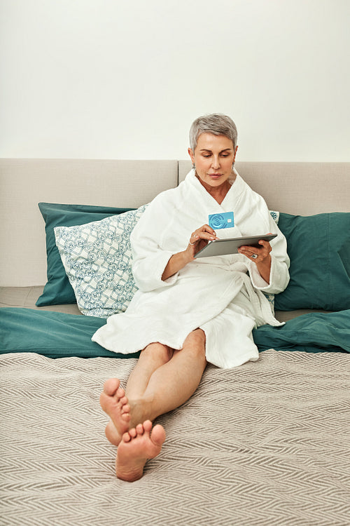 Senior woman with grey hair making an online purchase from bedroom