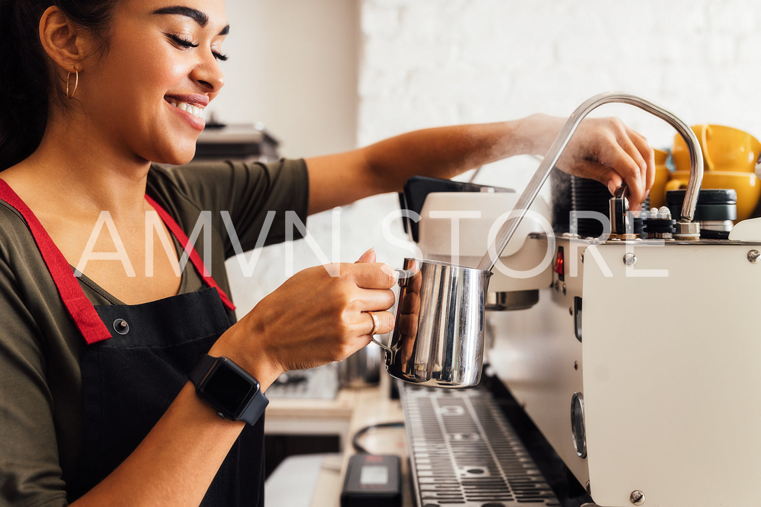 Close up of female barista making steamed milk holding a frothing pitcher	