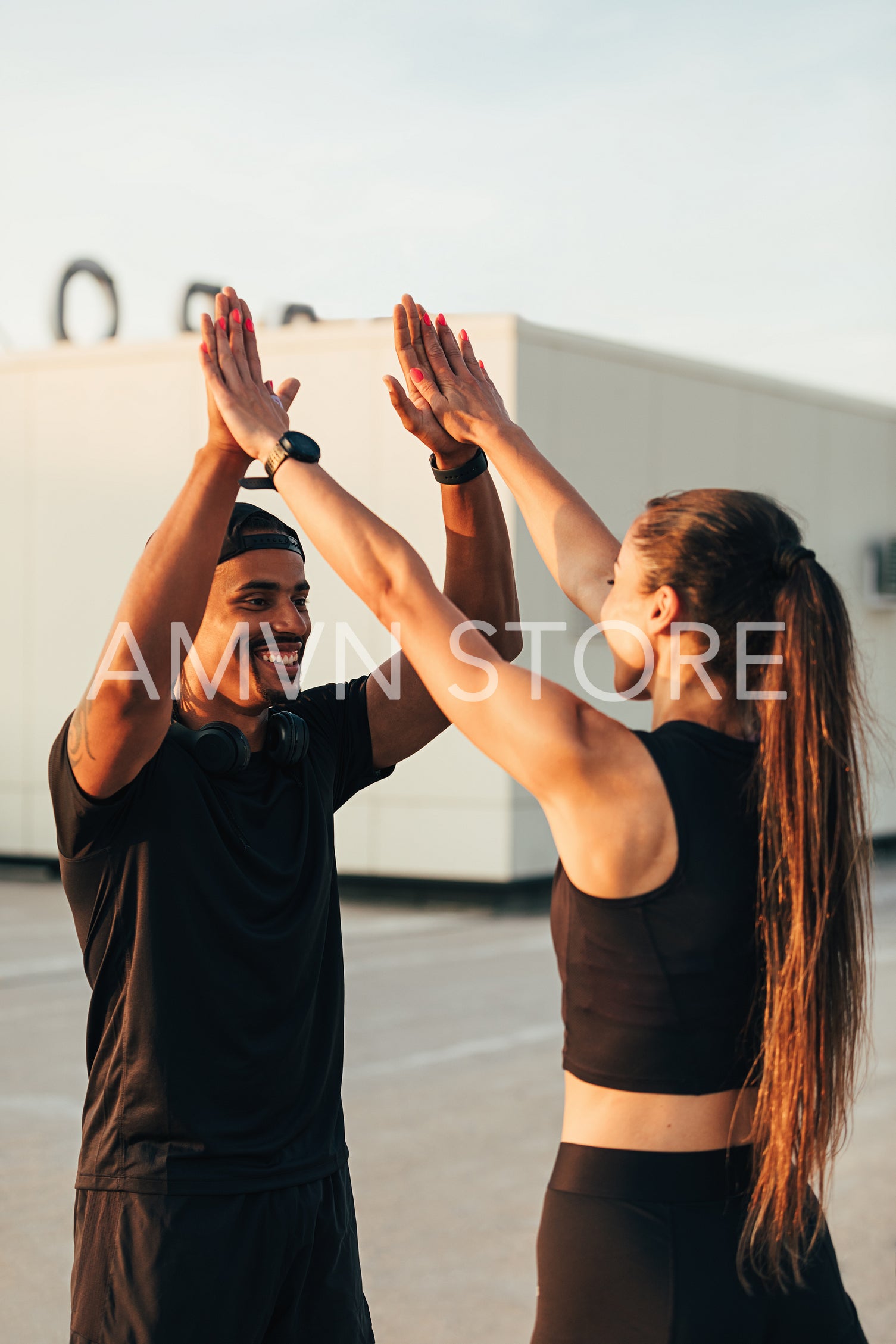 Two athletes in black sportswear giving high five on the roof