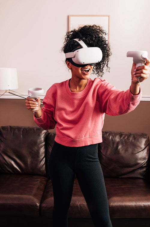 Woman with VR goggles and controllers in living room