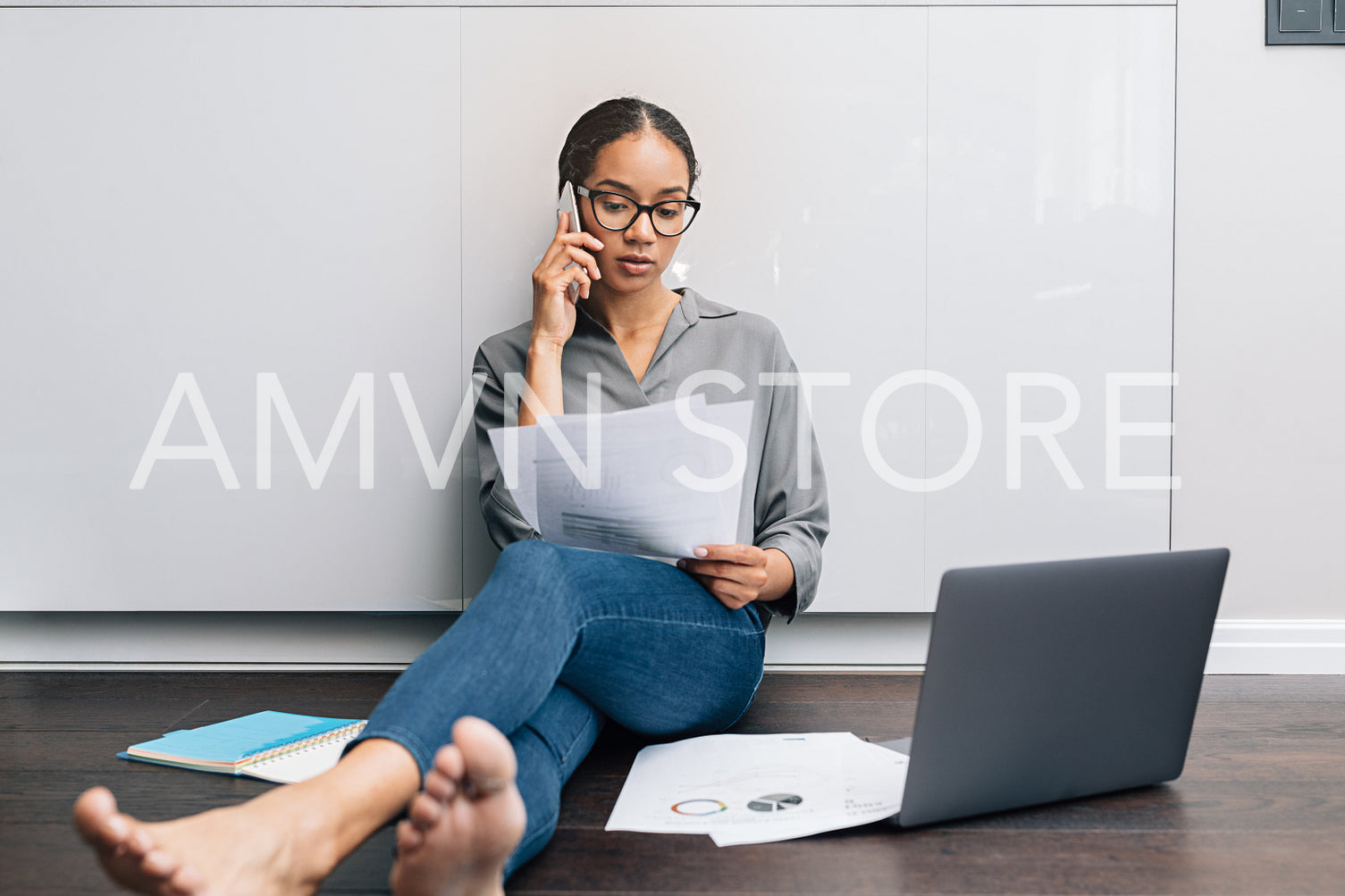 Self-employed woman looking on documents while talking on mobile phone	