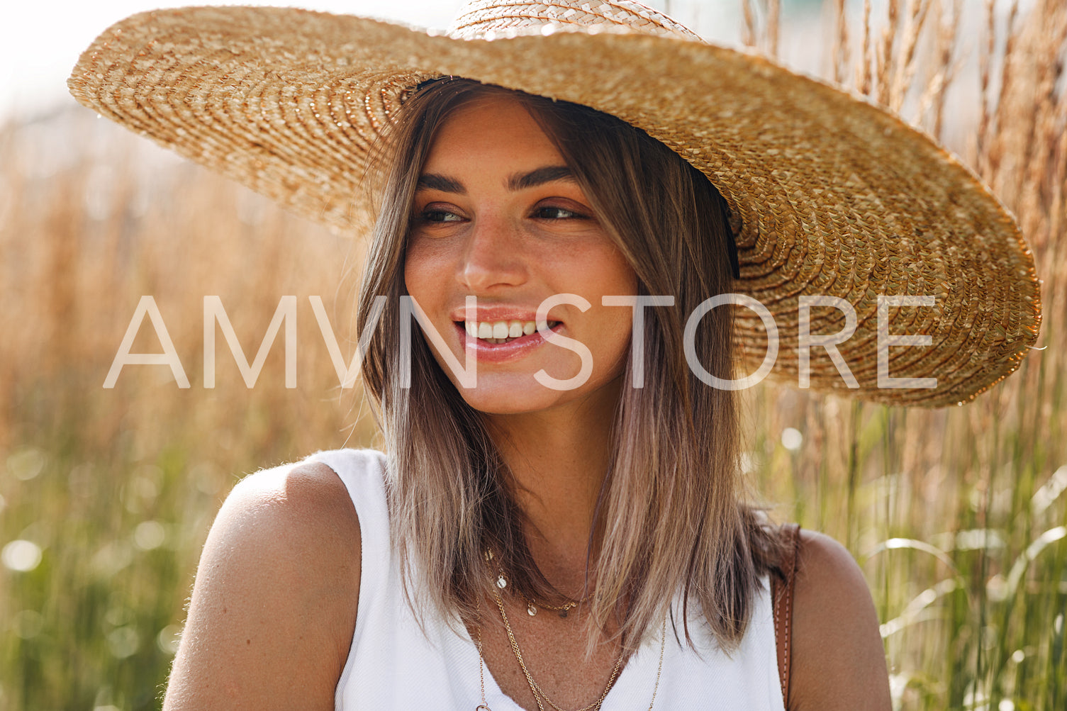 Close up portrait of a happy blond woman in sun hat looking away	