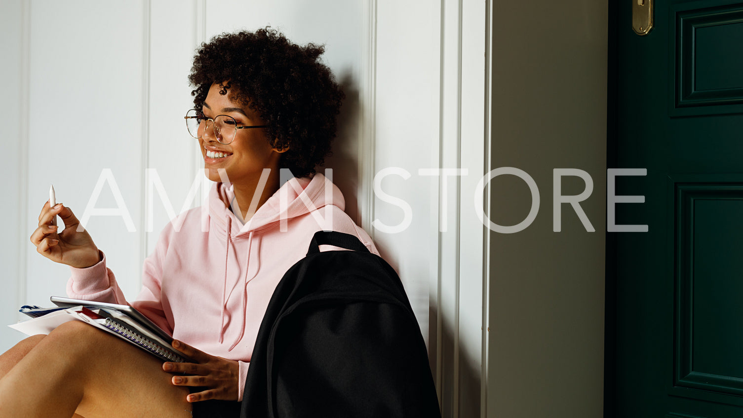 Smiling girl with books and digital tablet on her knees, looking away	