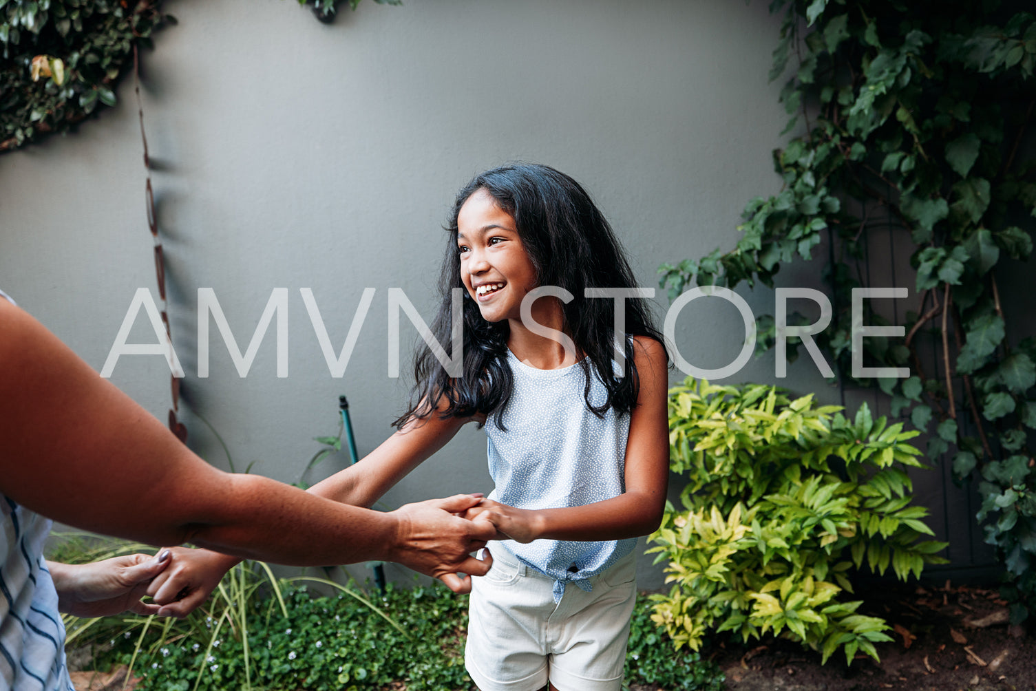 Smiling girl dancing with granny outside. Kid is having fun in the backyard.