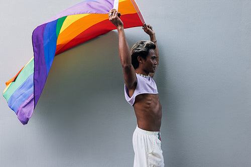 Stylish guy holding rainbow LGBT flag above his head