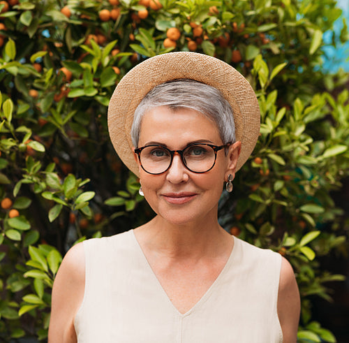 Portrait of a stylish senior woman in eyeglasses and a straw hat