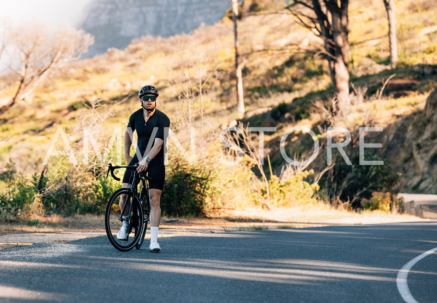 Young male cyclist relaxing during training on an empty road in wild terrain