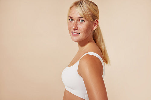 Beautiful blond woman with freckles posing in studio against pastel background