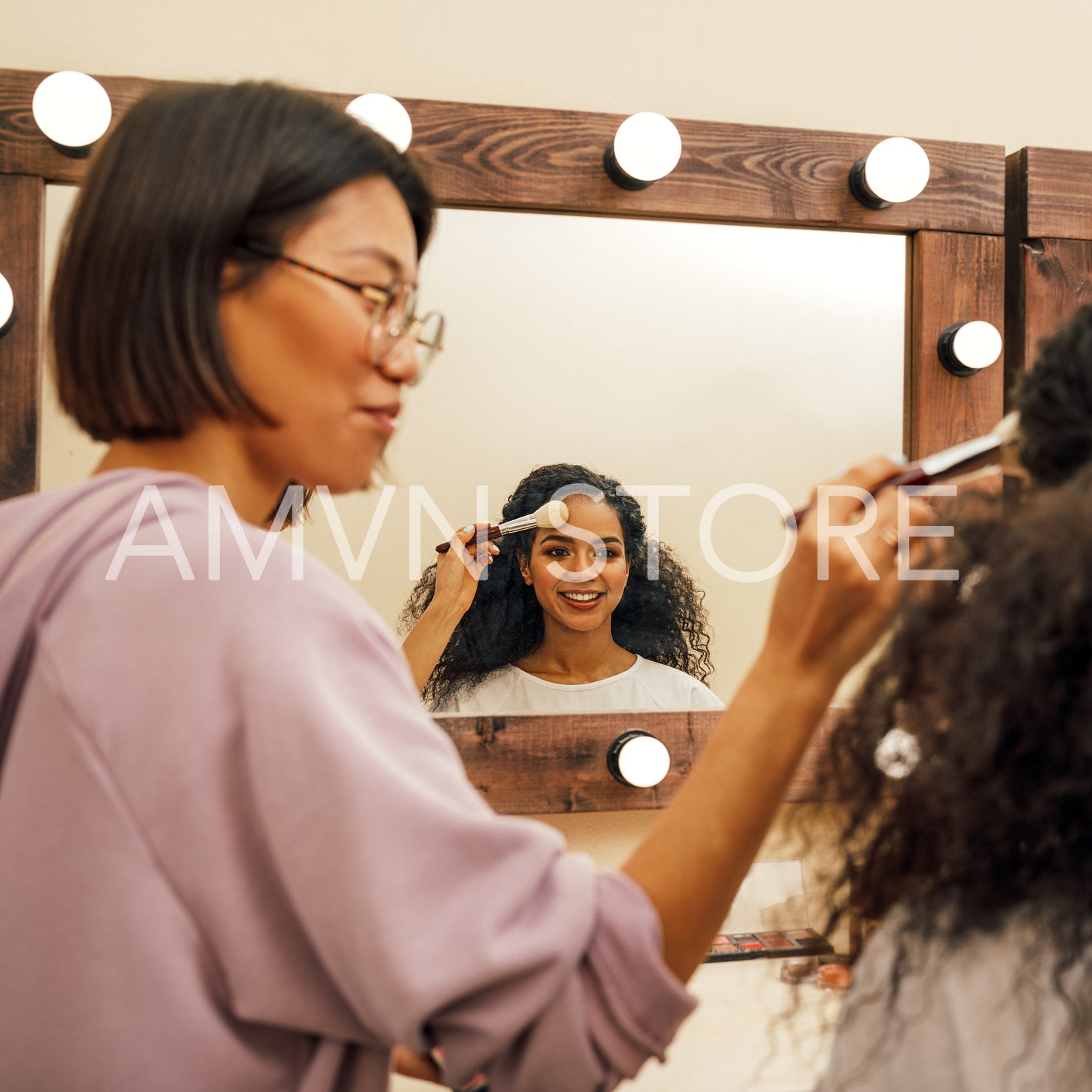 Make up artist and model preparing for photoshoot in dressing room	
