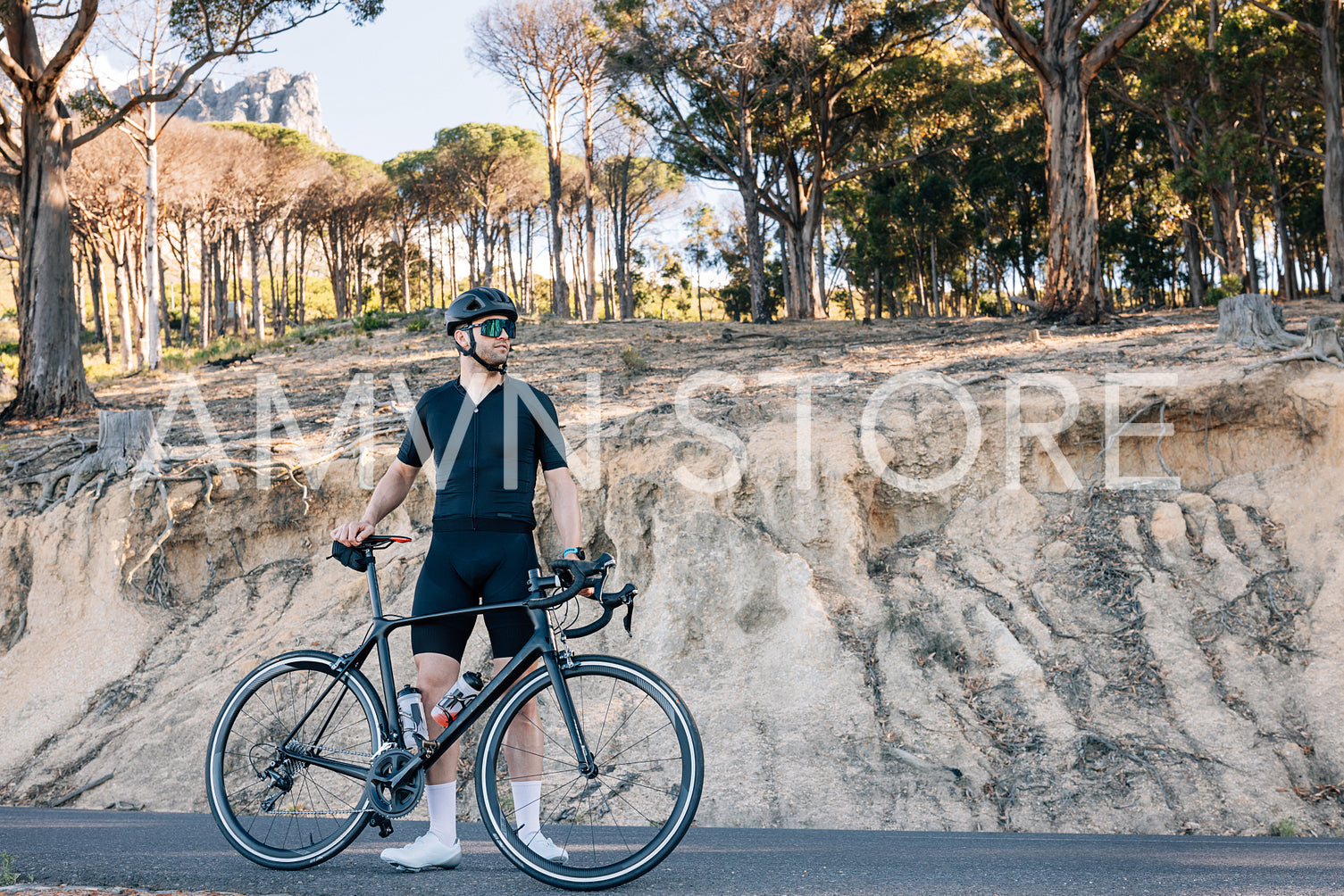 Athlete with road bicycle relaxing on a roadside looking away