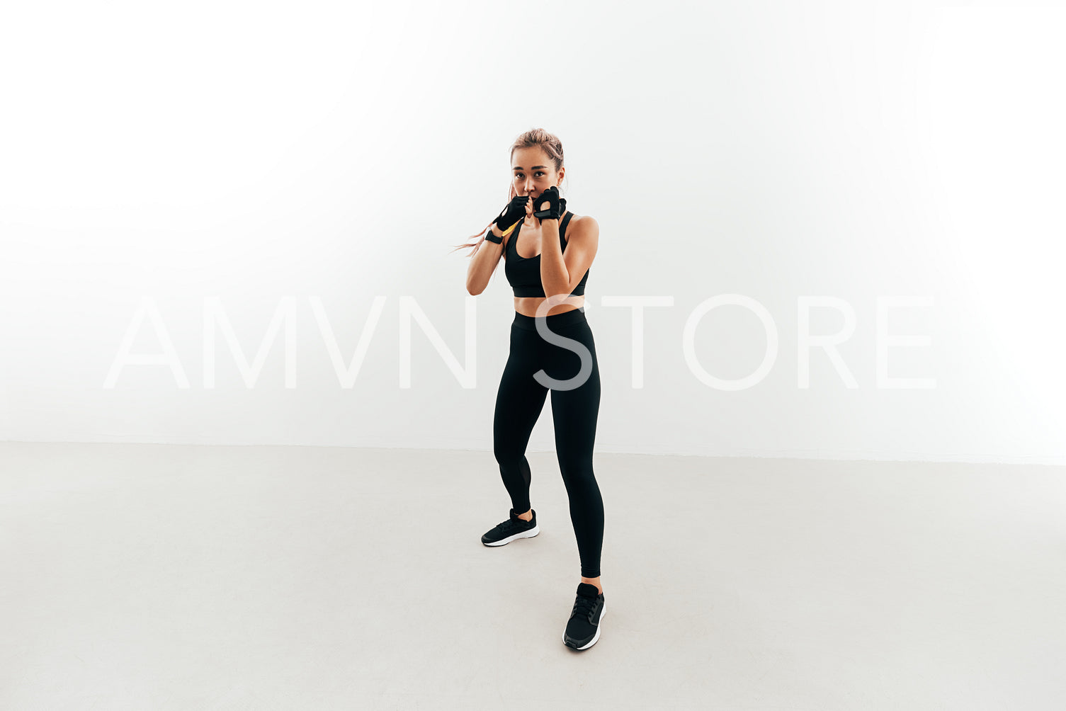 Shot of a female boxer holding a stance. Woman in gloves exercising indoors.