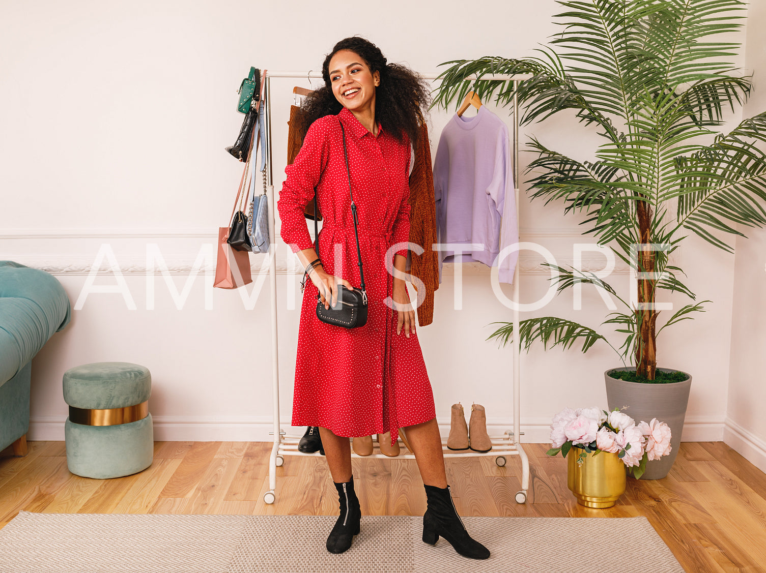 Personal stylist wearing red dress in studio. Woman posing at clothes rack.	