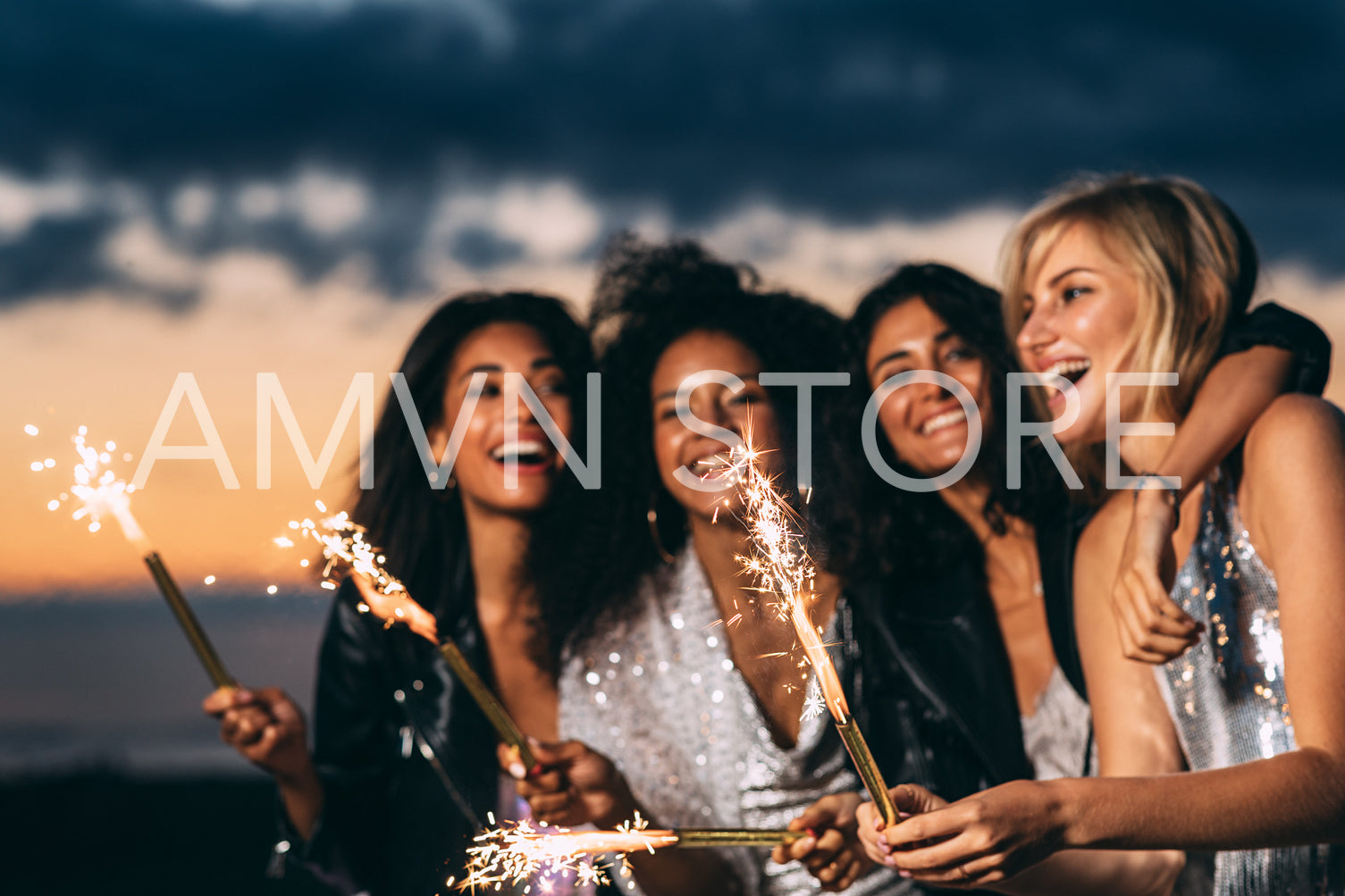 Close up of happy women holding sparklers at sunset	