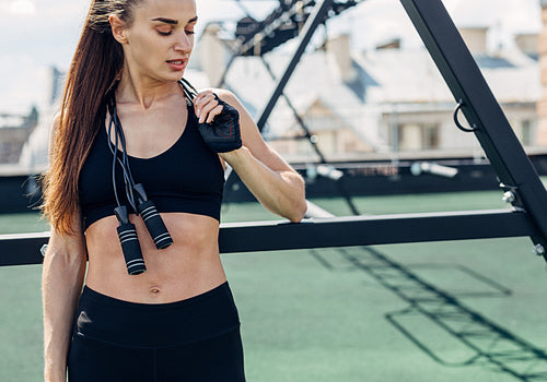 Fitness woman taking a break standing with jumping rope on her neck