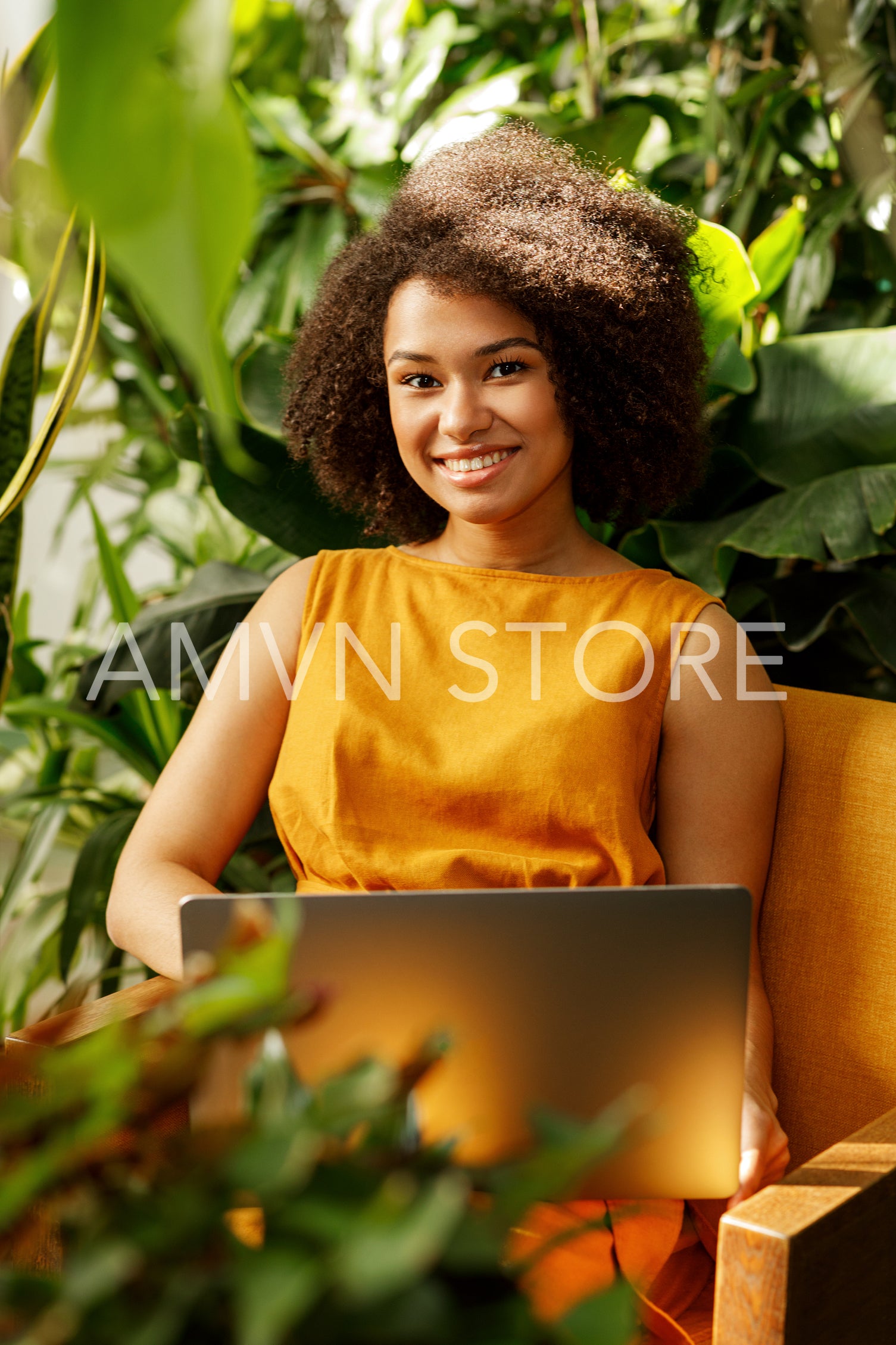 Smiling female florist sitting at her workshop and typing on laptop	