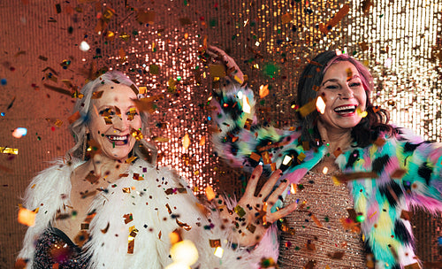 Senior females in fur coats celebrating together in studio under