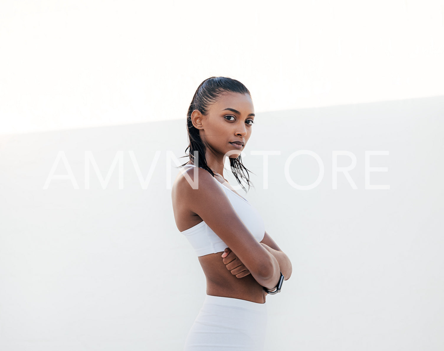 Confident sportswoman in white fitness attire with crossed arms