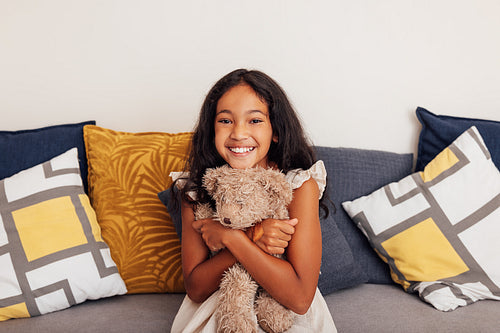 Portrait of a little girl hugging teddy bear and looking at camera