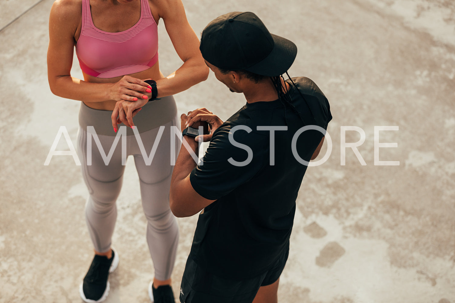 High angle of two people in sportswear checking their smartwatches after training