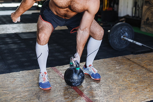 Unrecognizable fitness man working out with kettlebell in gym