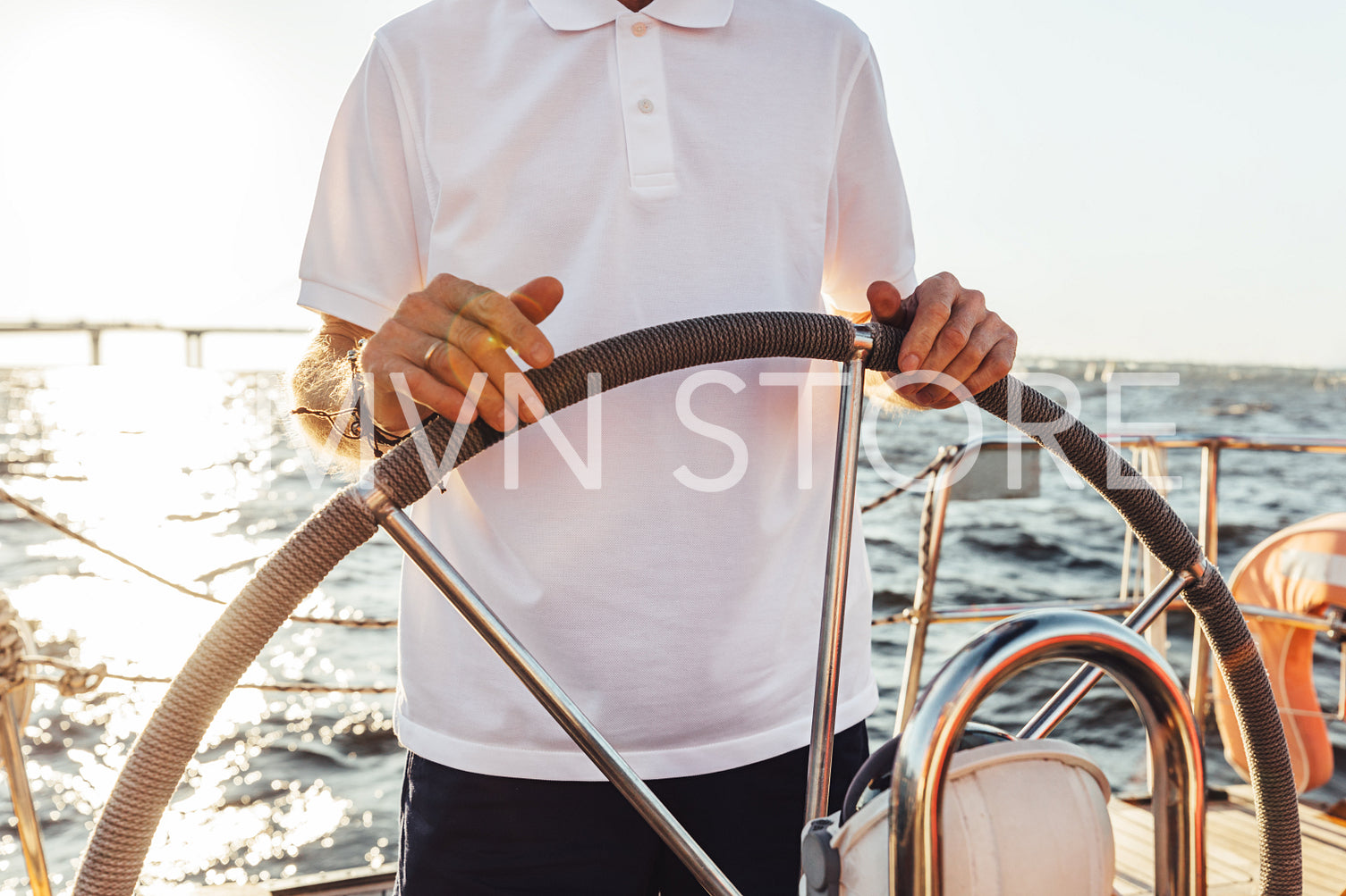 Unrecognizable man standing on a yacht and holding a steering wheel	