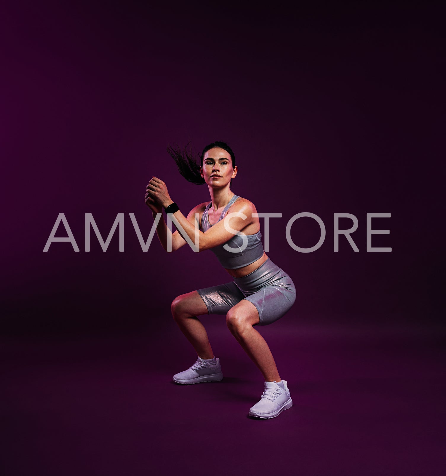 Full length of a slim female in silver sportswear doing sit-ups over a magenta background