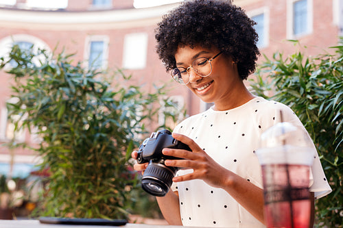 Young woman looking at digital camera while standing outdoors