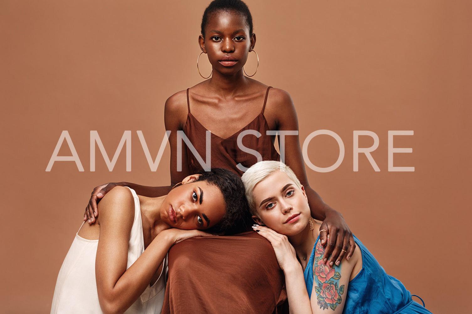 Three beautiful women posing together in a studio wearing dresses	