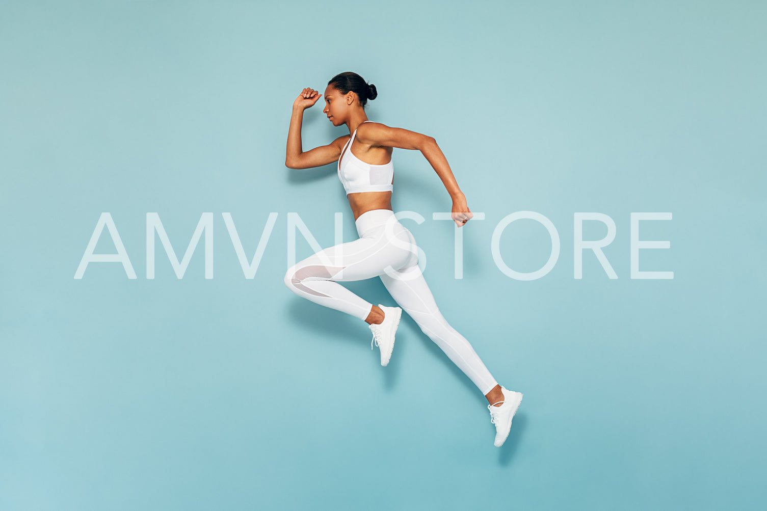 Sports woman running in studio. Full length shot of young female exercising over blue backgroud.