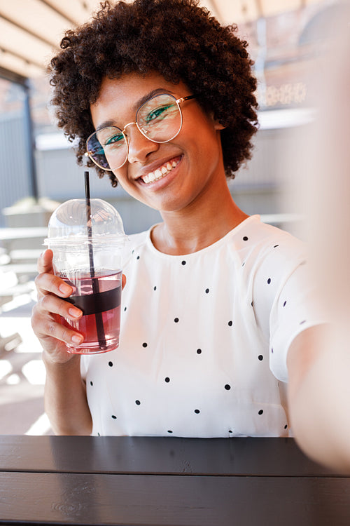 Smiling woman posing for a selfie with a drink in her hand